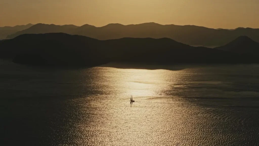A yacht in a path of sunlight between the Japanese islands